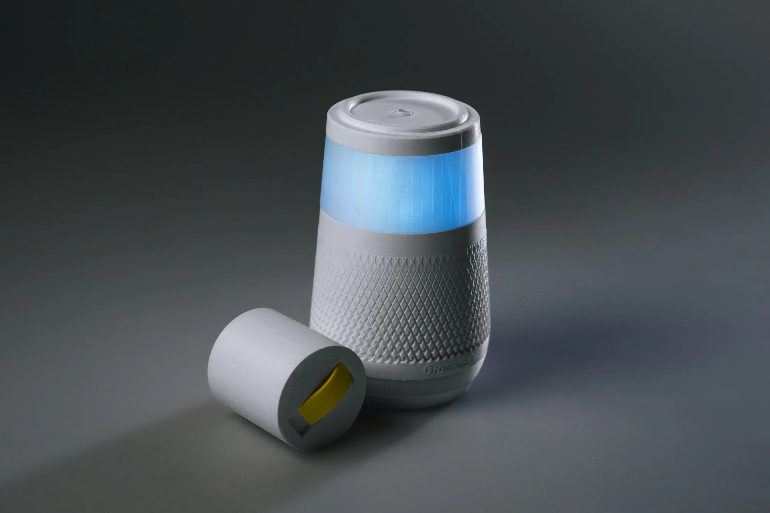 The OrderUP device and the small module lying on its side, on a dark grey background
