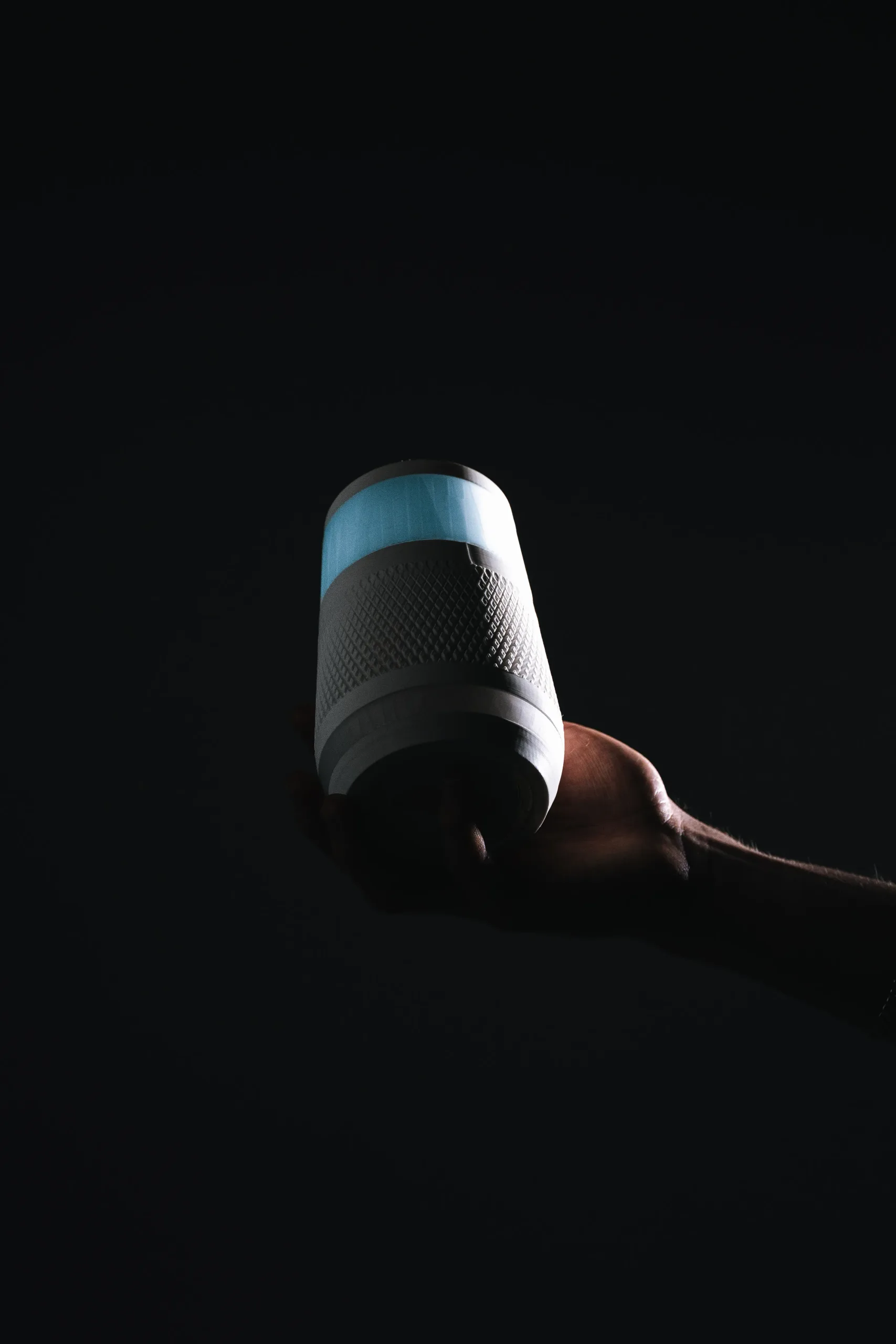 A hand holding the OrderUP device in the dark, its blue ring glowing