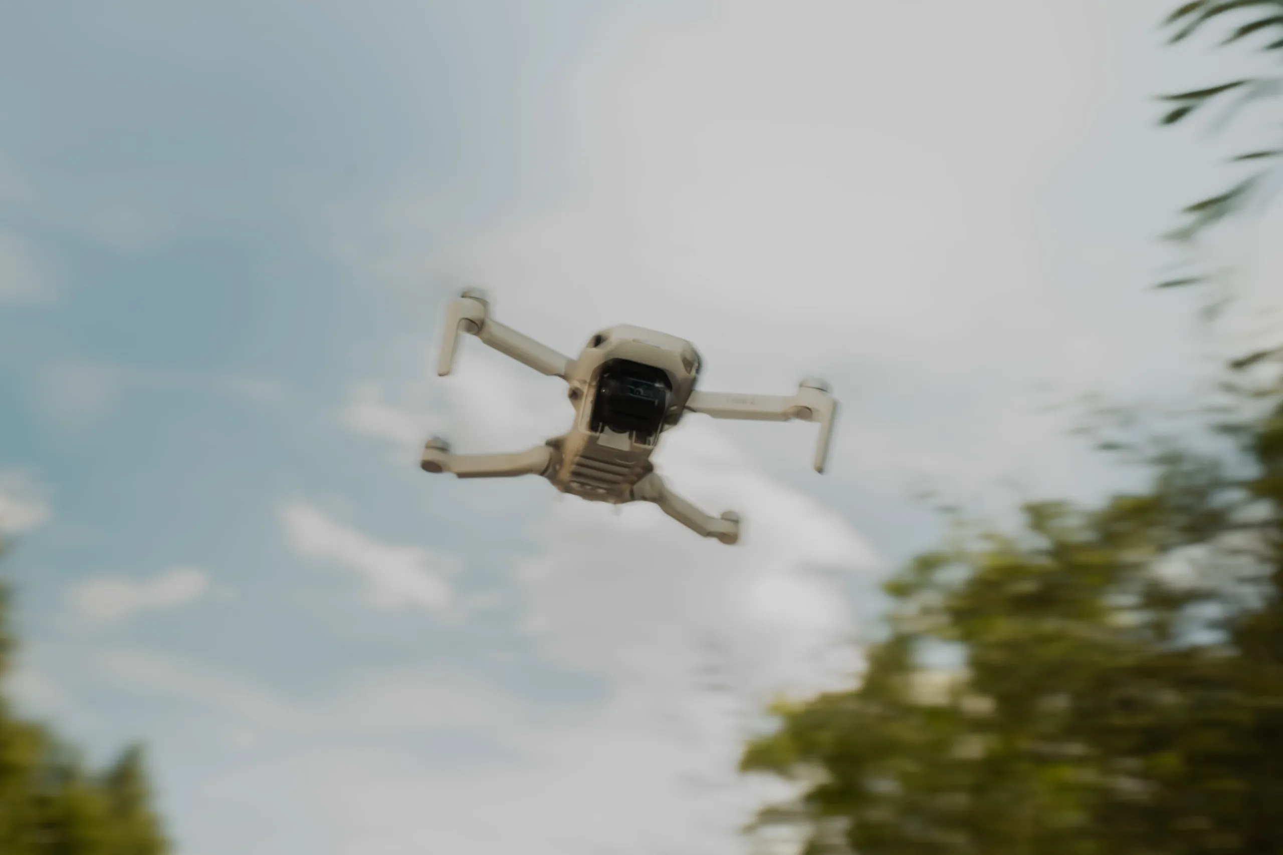 A small drone flying in front of a cloudy sky