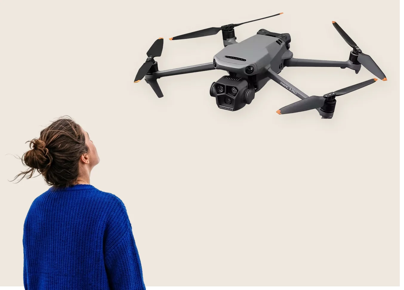 A person in a blue sweater looking up at a drone